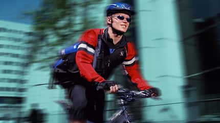 Male cycle courier riding along city street (Digital Composite) Male cycle courier riding along city street (Digital Composite)
