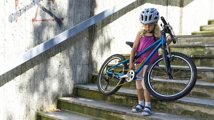 Kind trägt Fahrrad Treppe hinunter Kind trägt Fahrrad Treppe hinunter