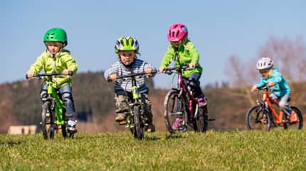 Vier Kinder fahren auf einer Wiese Fahrrad Vier Kinder fahren auf einer Wiese Fahrrad
