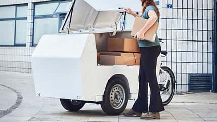 Paketzustellerin lädt Pakete in E-Lastenrad Paketzustellerin lädt Pakete in E-Lastenrad