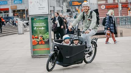 E-Lastenrad I Test Riese und Müller Packster 70 Vario I Fahrbild Mann und 2 Kinder unterwegs E-Lastenrad I Test Riese und Müller Packster 70 Vario I Fahrbild Mann und 2 Kinder unterwegs