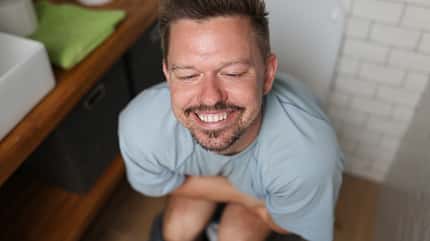 laxative,microflora,gastritis,encopresis Man with satisfied smile sits on toilet