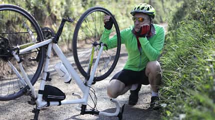 cycling clothes Man looking at bicycle with damaged wheel