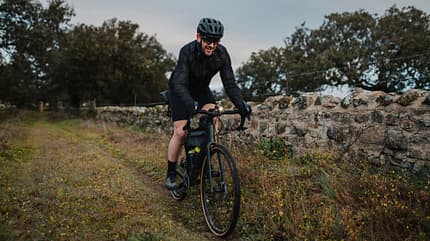Smiling cyclist riding bicycle by wall Smiling cyclist riding bicycle by wall