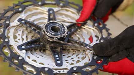 Bikehack, Tipp, Freilauf, Klinke, zusammenziehen, Der Freilauf einer Kassette wird mithilfe eines Schnürsenkels angebracht, indem die Sperrklinken zurückgedrückt werden.