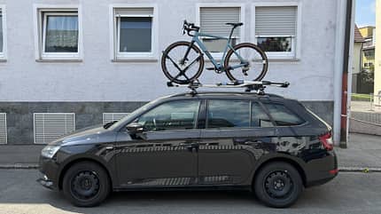 Gravelrad auf einem schwarzen Kombi-Autodach Gravelrad auf einem schwarzen Kombi-Autodach