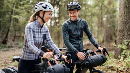 Couple with gravel bilkes in the forrest on a bike packing trip Couple with gravel bilkes in the forrest on a bike packing trip