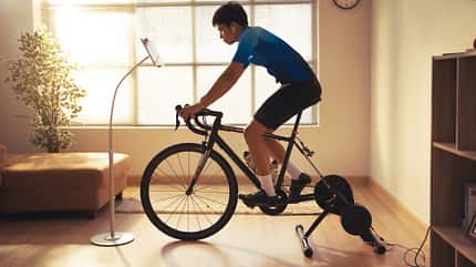 Asian man cyclist. he is exercising in the house.By cycling on the trainer and play online bike games Asian man cyclist. he is exercising in the house.By cycling on the trainer and play online bike games