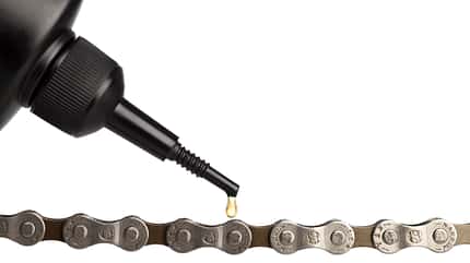 horizontal,horizontal image,nobody,no one,no-one,transportation,transport,bicycle chain,chain,bike chain,metal,close up,close-up,closeup,close up shot,close-up shot,closeup shot,close up view,close-up view,closeup view,studio shot,studio shots,white background,plain background,lubricant,oil,dripping,droplet,precision,improvement,lubrication,lubricating Lubricant oil and bicycle chain