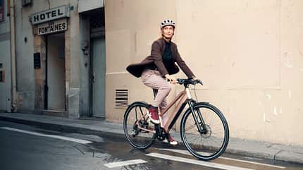 Frau fährt mit stylishem City-E-Bike von Riese und Müller durch die Stadt. E-Bike-Trends 2025.
