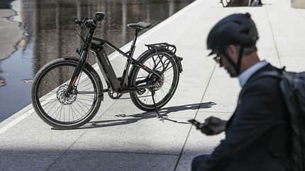 Mann verbindet sich über sein Smartphone mit seinem E-Bike Mann verbindet sich über sein Smartphone mit seinem E-Bike
