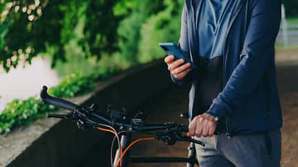 Young man with bike using smartphone