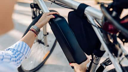 E-Bike, Akku, Batterie, Elektrofahrrad, Mobilität, Technik, Energie, Fahrradakku, Ladevorgang, Nachhaltigkeit, moderne Mobilität, Handhabung, Elektromobilität, Alltag, Fahrradrahmen, Detailaufnahme Nahaufnahme einer Person, die den Akku eines E-Bikes aus dem Rahmen entnimmt oder einsetzt.