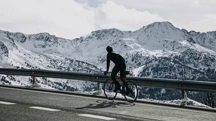 active,ambition,bike,cloud,cold,exercise,fit,goal,health,healthy,high,landscape,lane,leisure,summit,training,view Andorra, cyclist on mountain road with snowy mountains in the background