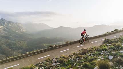 Mature cyclist on a steep climb in the Spanish mountains at sunset Mature cyclist on a steep climb in the Spanish mountains at sunset