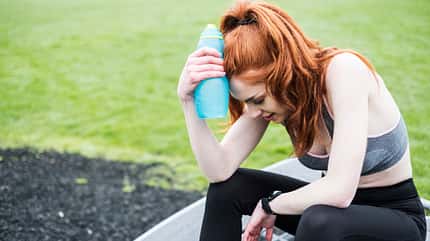 energy,female,fitness,health,red hair,tiredness,youth Young woman with long red hair wearing sportswear, exercising outdoors.