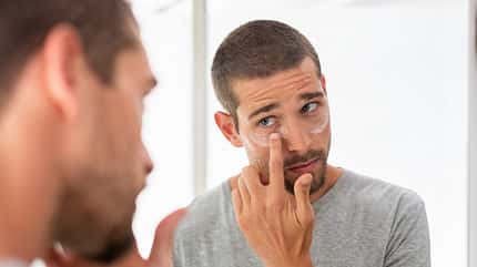 Man applying moisturizer under eyes