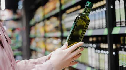 Frau, die sich für natürliches Olivenöl oder Traubenkernöl im Geschäft entscheidet. Frau, die sich für natürliches Olivenöl oder Traubenkernöl im Geschäft entscheidet.