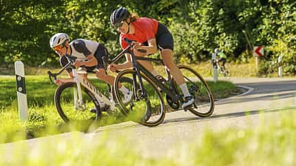 Zwei Rennradfahrende in einer Kurve Zwei Rennradfahrende in einer Kurve
