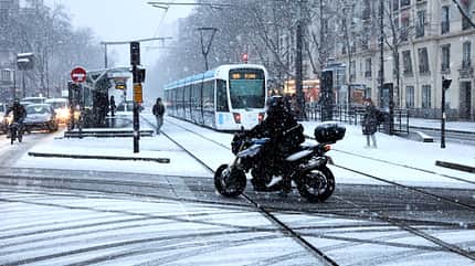 Ein Motorradfahrer fährt mit seinem Motorrad während des ersten Schneefalls dieser Wintersaison in Paris, Frankreich. 