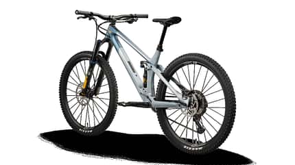 Das Bild zeigt ein YT IZZO 29 CF Core 3 Mountainbike in der Farbvariante Mizu Silver, fotografiert von schräg hinten mit Fokus auf Rahmen, Federung und Antrieb.