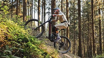 Ein Fahrer erklimmt mit einem Propain Ekano E-Mountainbike einen steilen Waldrand in Beerfelden. Das Bild zeigt eine dynamische Uphill-Szene im Wald mit Fokus auf das E-MTB und die sportliche Fahrtechnik.