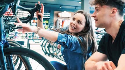man showing female customer new racing bike in bikeshop man showing female customer new racing bike in bikeshop