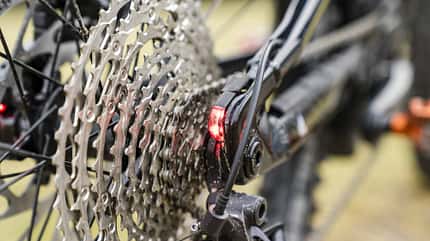 Detailaufnahme einer Mountainbike-Kassette mit Schaltwerk und Rücklicht, Fokus auf die Ritzel.