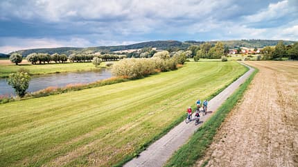 Panoramabild einer Gruppe, die durch Felder neben der Weser radelt 