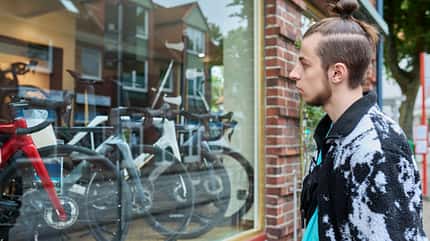 Young male looking dreamily at modern bicycles in shop window