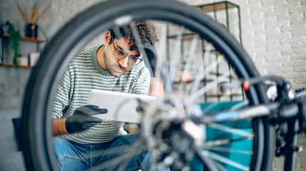 Man tries to repair bicycle at home using tablet