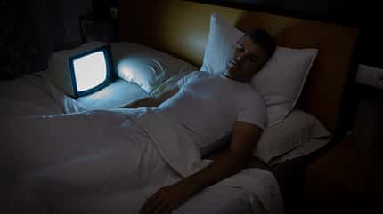 A man sleeps with the TV with no signal on in bed at night. Vintage TV