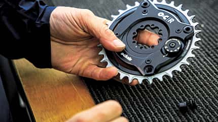 Detailaufnahme eines Fahrrad-Kettenblatts von SRAM, gehalten von einer Hand, aufgenommen beim RockShox Sram Presscamp 2026 in Queenstown, Neuseeland.