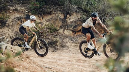 Mondraker E-Gravelbike Dusty,zwei Fahrer in Kurve Mondraker E-Gravelbike Dusty,zwei Fahrer in Kurve