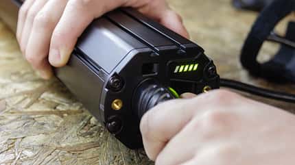 Close up shoto of male hands plugging in charger to an electric bicycle battery Close up shoto of male hands plugging in charger to an electric bicycle battery