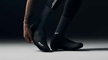 Radfahrer beim Anziehen schwarzer MAAP Apex Winter Overshoes.