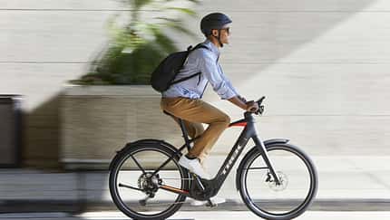 Mann mit Rucksack in der Stadt auf einem E-Bike Trek Allant+