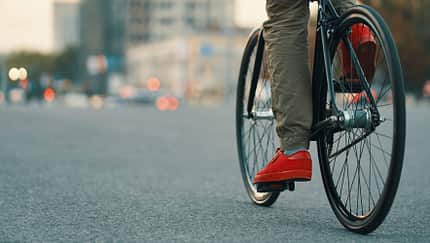 Closeup of casual man legs riding classic bike on city road