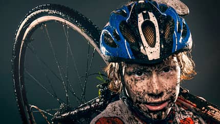 Mud splattered cyclist carrying bicycle