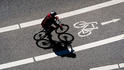High Angle View Of Man Cycling On Bicycle Lane During Sunny Day