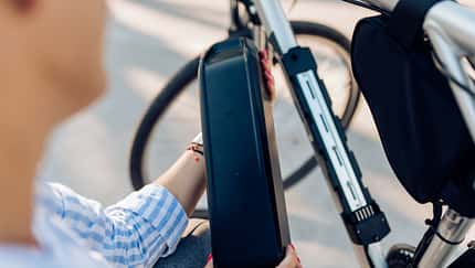 Unrecognizable woman changing batteries on her electric bicycle