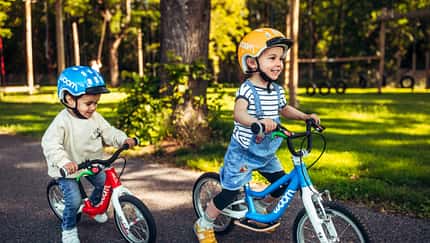 Zwei Kinder fahren auf ihrem Woom Laufrad