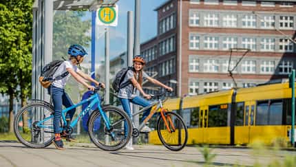 Zwei Jugendliche mit Puky Fahrrad an Bushaltestelle