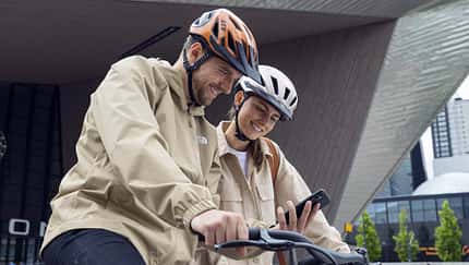 Mann und Frau mit Fahrrad tragen Abus Fahrradhelm