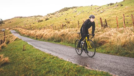 Young caucasian cyclist man climbing a hill in a foggy mountain.