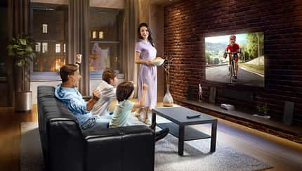 Family with children cheering and watching Cycle race on TV