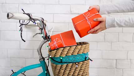 Santa's helper packing parcel of Christmas presents on bicycle