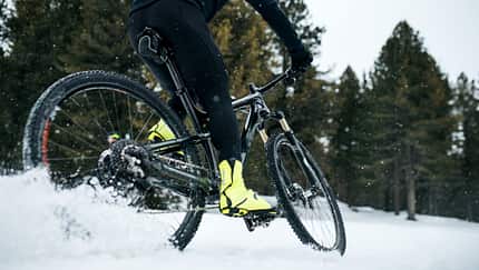 Midsection of mountain biker riding in snow outdoors in winter.