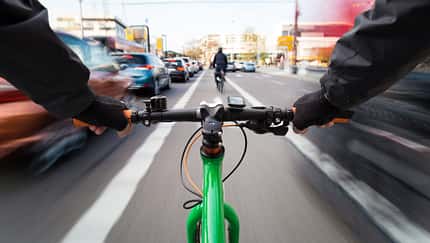 Cyclist drives on the bike path past the traffic jam - First-person view of cyclist/ motion blur