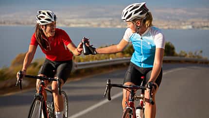 Cyclist passing water bottle to training partner